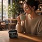 Mellow Monkey GO Air POP black wireless earbuds worn by a woman holding a coffee cup in a cozy cafe setting