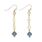 Mellow Monkey gold drop earrings featuring blue clover charms and delicate metal links for a coastal style.