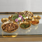 Mellow Monkey gold-plated alloy cluster of nine serving bowls filled with snacks and flowers on a glass table