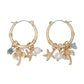 Mellow Monkey gold hoop earrings featuring coastal charms like palm trees, starfish, and pearls for a beachy style.