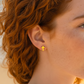 Mellow Monkey minimalist 18k gold cross stud earrings worn by a woman with red hair on a sunny beach