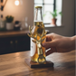 Mellow Monkey gold cast aluminum deer head bottle opener held against a beer bottle on a wooden counter