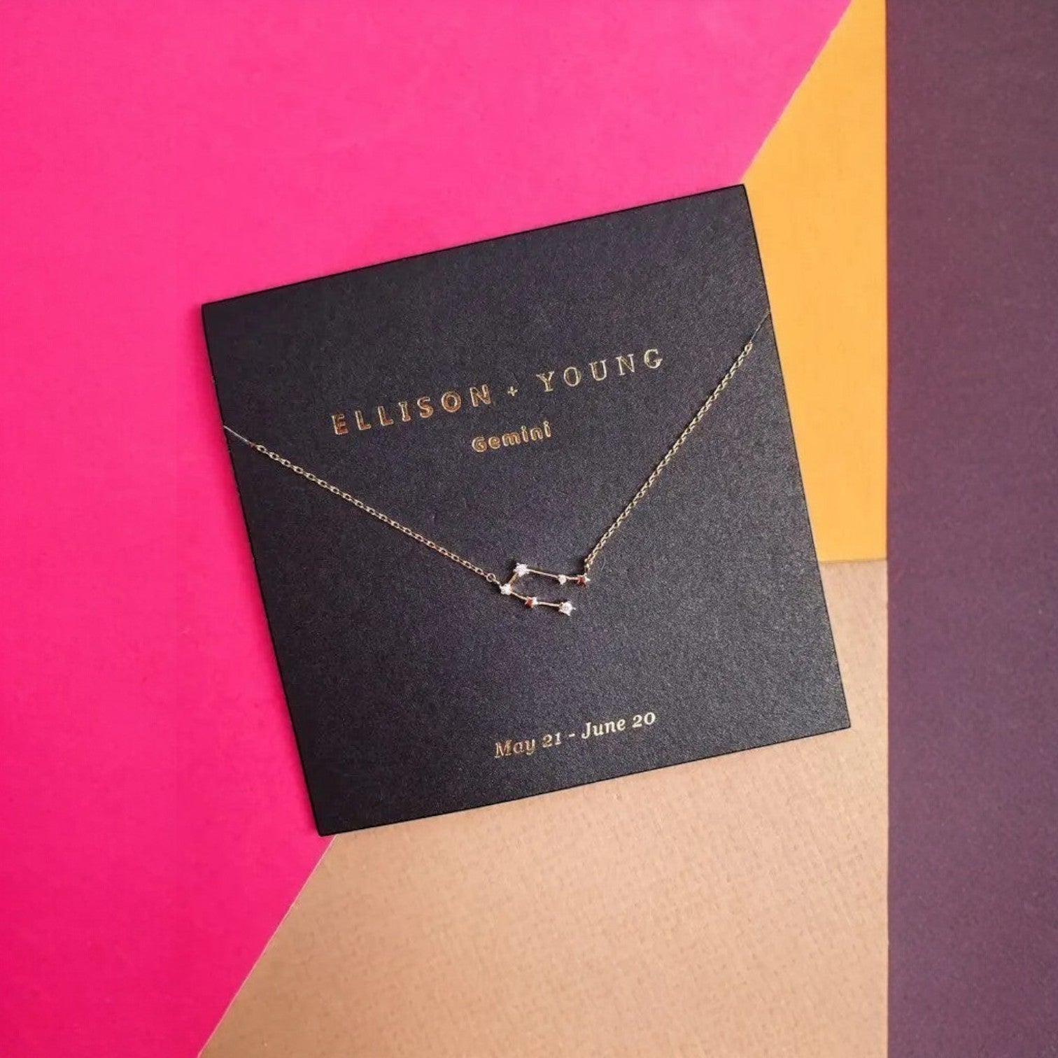 Mellow Monkey gold Gemini constellation necklace with cubic zirconia accents on a black card.