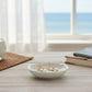 Mellow Monkey gold open scallop earrings with white pearls displayed in a small white dish by a beach view window.