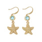 Mellow Monkey gold starfish drop earrings featuring sparkling aqua crystals on hook backings for a coastal style.