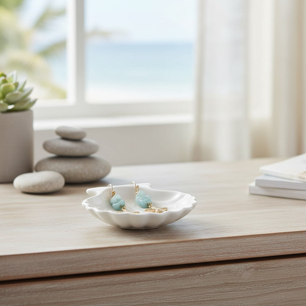Mellow Monkey gold starfish earrings with light blue semiprecious stones resting in a white ceramic shell dish.
