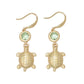 Mellow Monkey gold turtle drop earrings featuring a round green crystal accent, nickel-free coastal jewelry.