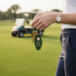 Mellow Monkey retro motel-style green keychain with Golf Cart Keys text held on a golf course
