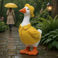 Mellow Monkey hand-painted resin goose garden statue wearing a yellow raincoat and hat in a rainy outdoor setting