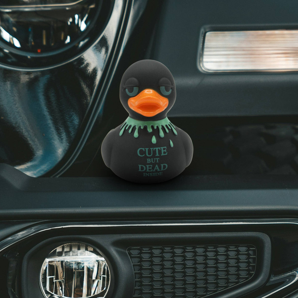 Mellow Monkey gothic rubber duck with neon green blood drips and Cute But Dead Inside text on a car dashboard