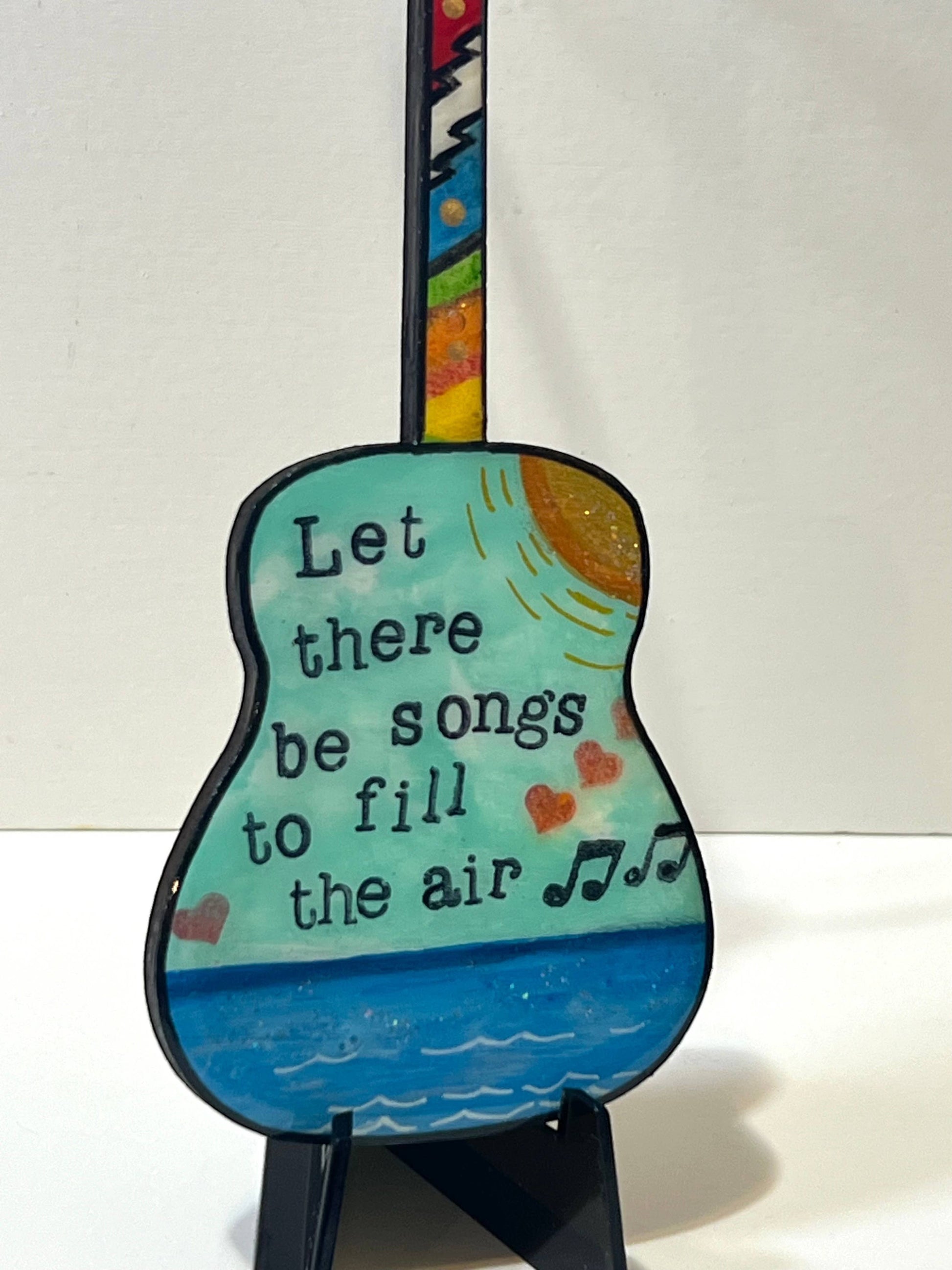 Mellow Monkey Grateful Dead wooden guitar ornament featuring hand-painted lyrics and a colorful fretboard on an easel.