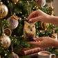 Mellow Monkey 4-inch gray owl ornament made from natural bottle brush fibers hanging on a decorated Christmas tree