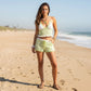 Mellow Monkey green and white striped crochet bikini top and shorts set worn by a woman on a sunny beach.