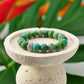 Mellow Monkey tropical green polymer clay bead stretch bracelet with a sparkling crystal center bead on a stone stand.