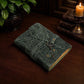 Mellow Monkey green embossed leather journal with a vintage key closure and deckle edge paper on a dark wooden table.