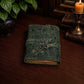 Mellow Monkey green embossed leather journal with a vintage key closure and deckle edge paper on a wooden desk.