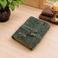 Mellow Monkey green embossed leather journal with a vintage key closure and deckle edge paper on a wooden desk.
