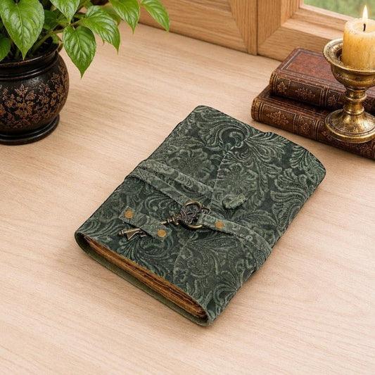 Mellow Monkey green embossed leather journal with a vintage key closure and deckle edge paper on a wooden desk.