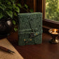 Mellow Monkey green embossed leather journal with a vintage key closure and deckle edge paper on a wooden desk.