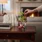 Mellow Monkey 8-inch green glass Christmas tree with hanging holiday icon ornaments and a Santa figure base