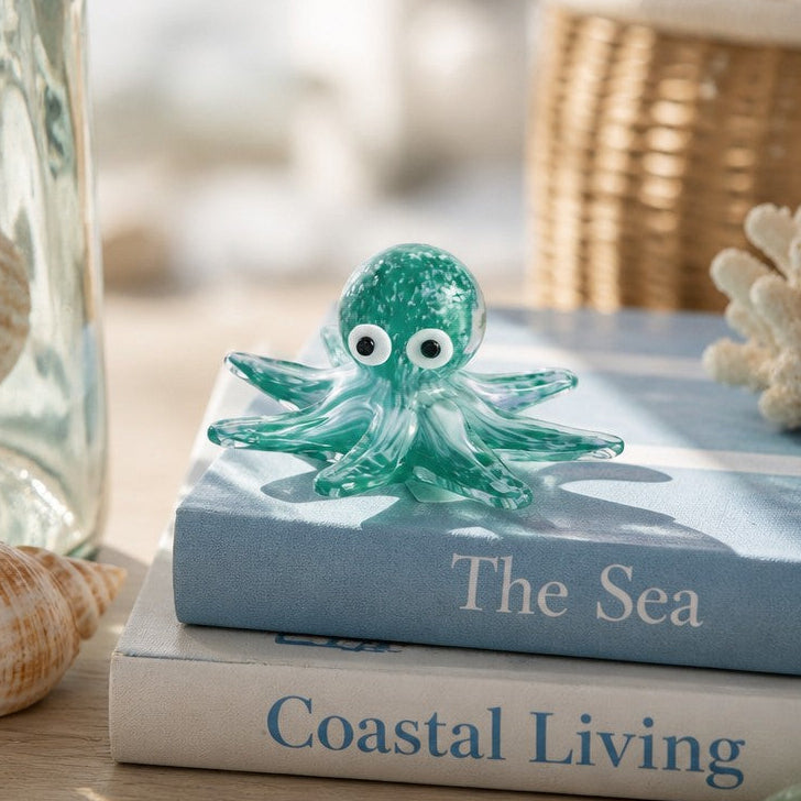 Mellow Monkey green glass octopus figurine resting on coastal books with seashells and coral decor
