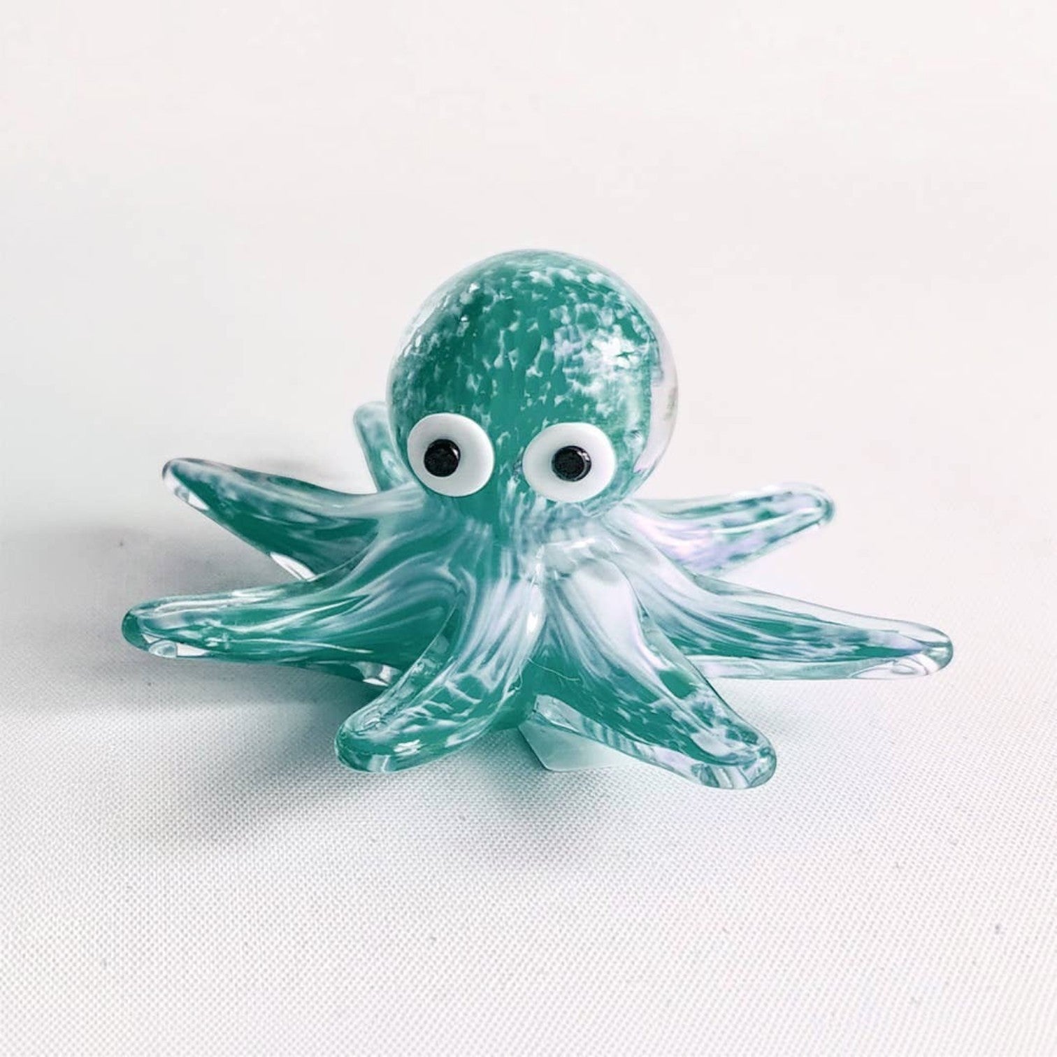 Mellow Monkey green glass octopus figurine with white and black eyes, detailed swirling patterns on a white background.