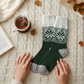 Mellow Monkey Green Ivory Holiday Crew socks with a festive snowflake pattern on a cozy cream cable knit background.