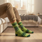 Mellow Monkey green crew socks featuring a pickle jar graphic and Big Dill Energy text worn by a person on a bed