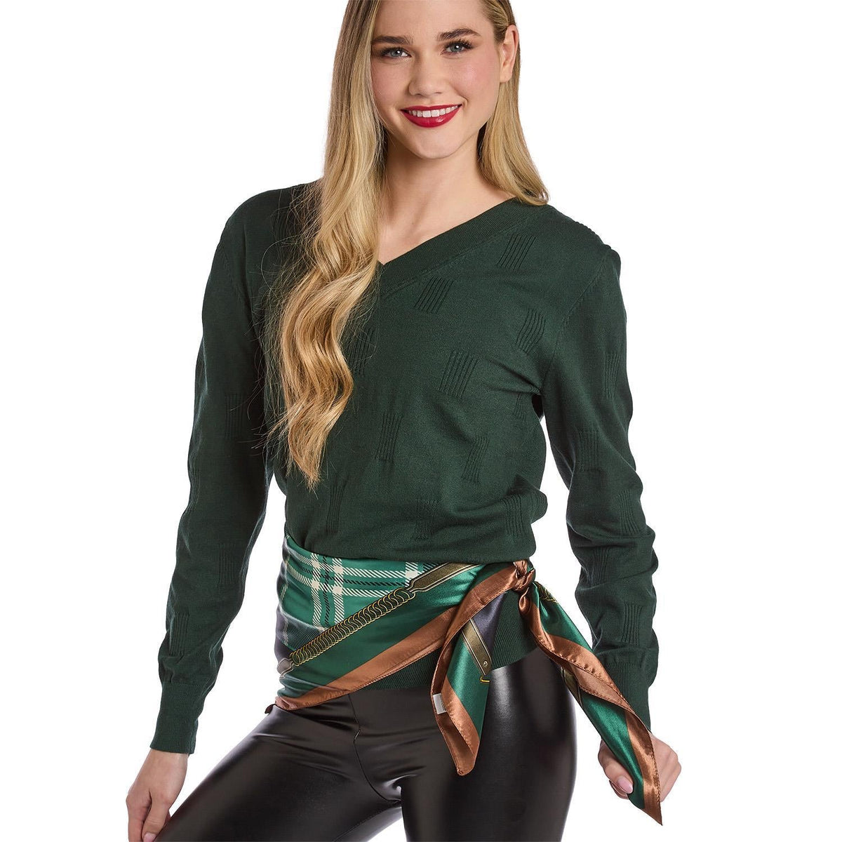 A woman wearing a Mellow Monkey green tartan silky scarf tied at her waist over a dark green sweater and black pants.
