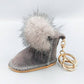 Mellow Monkey grey suede-like boot keychain with fluffy grey pom-pom accent and gold hardware.