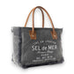 Mellow Monkey grey canvas crossbody bag with brown leather handles and frayed edges featuring vintage French typography