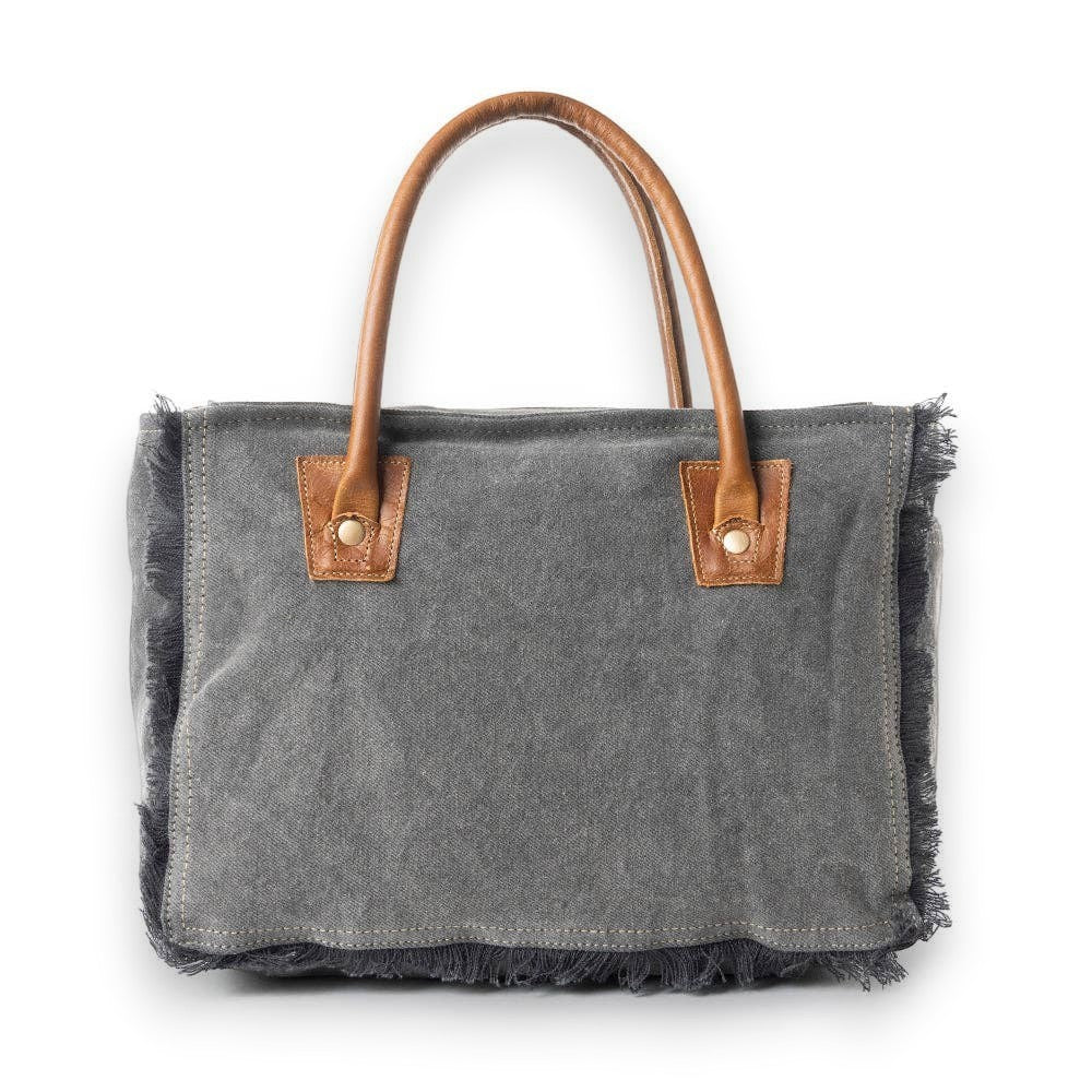 Mellow Monkey grey canvas crossbody bag with brown leather handles and frayed edge detailing on a white background.