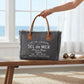 Mellow Monkey grey canvas crossbody bag with leather handles and frayed edges, displayed on a wooden bench.