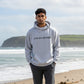 Mellow Monkey grey unisex hoodie with "you are enough" text, worn by a man walking on a beach.