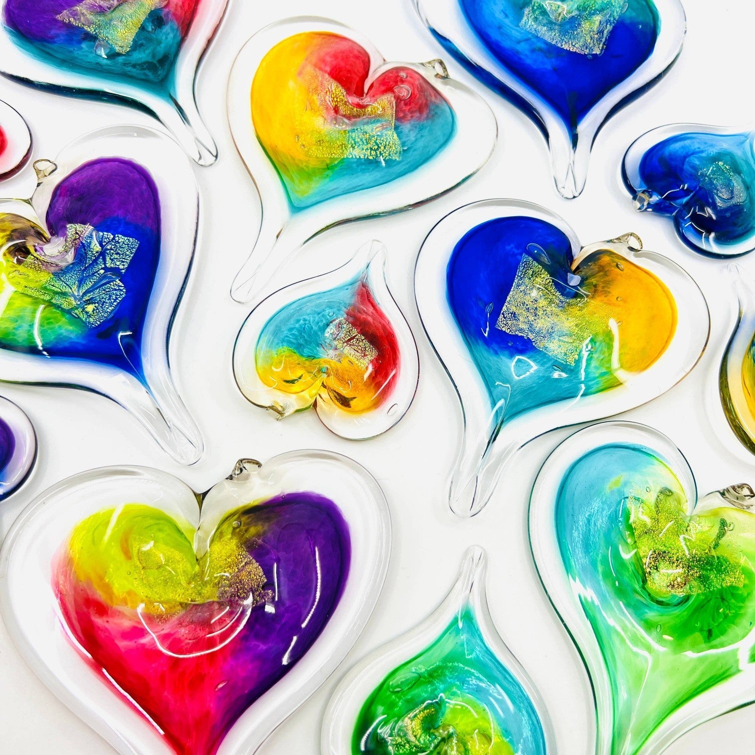 Mellow Monkey hand-blown glass heart ornaments in vibrant multi-colored swirls with gold leaf accents.