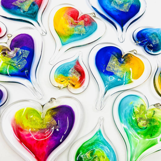 Mellow Monkey hand-blown glass heart ornaments in vibrant multi-colored swirls with gold leaf accents.