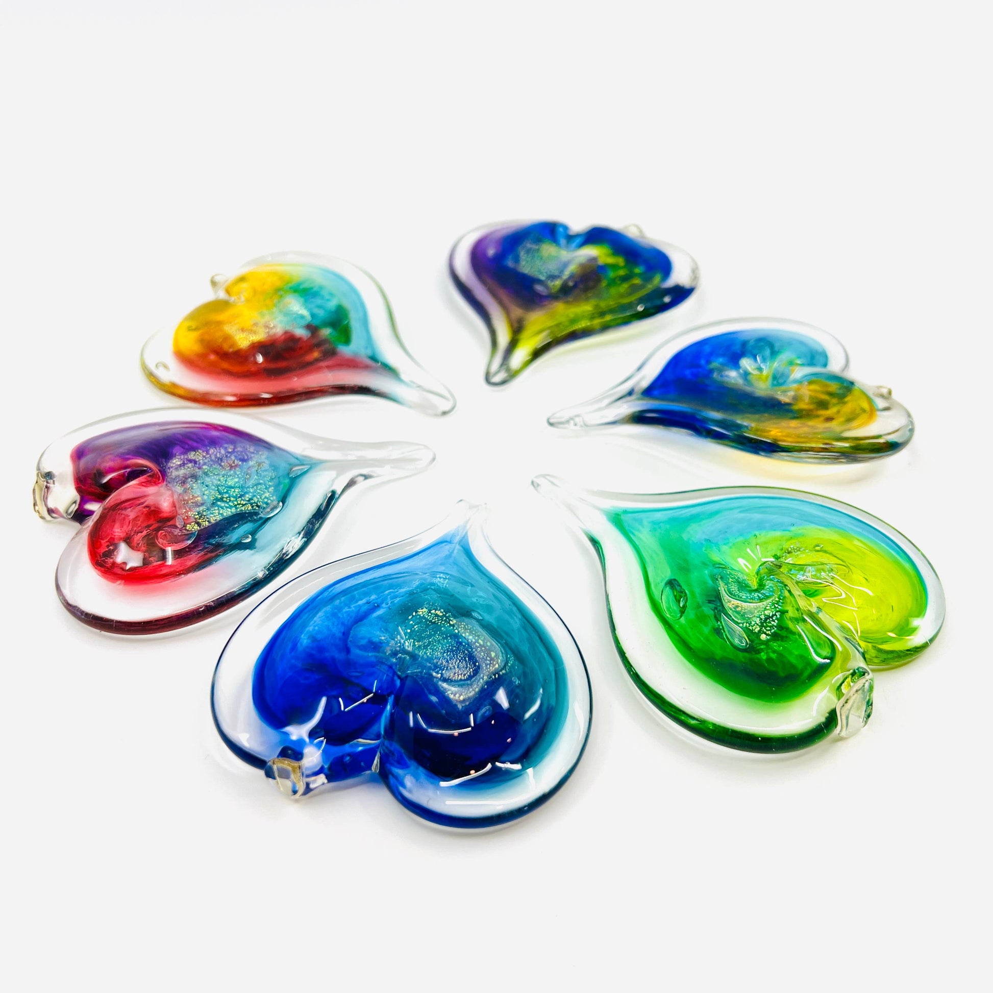 Mellow Monkey hand-blown glass heart ornaments in various vibrant colors with hanging loops on a white background.