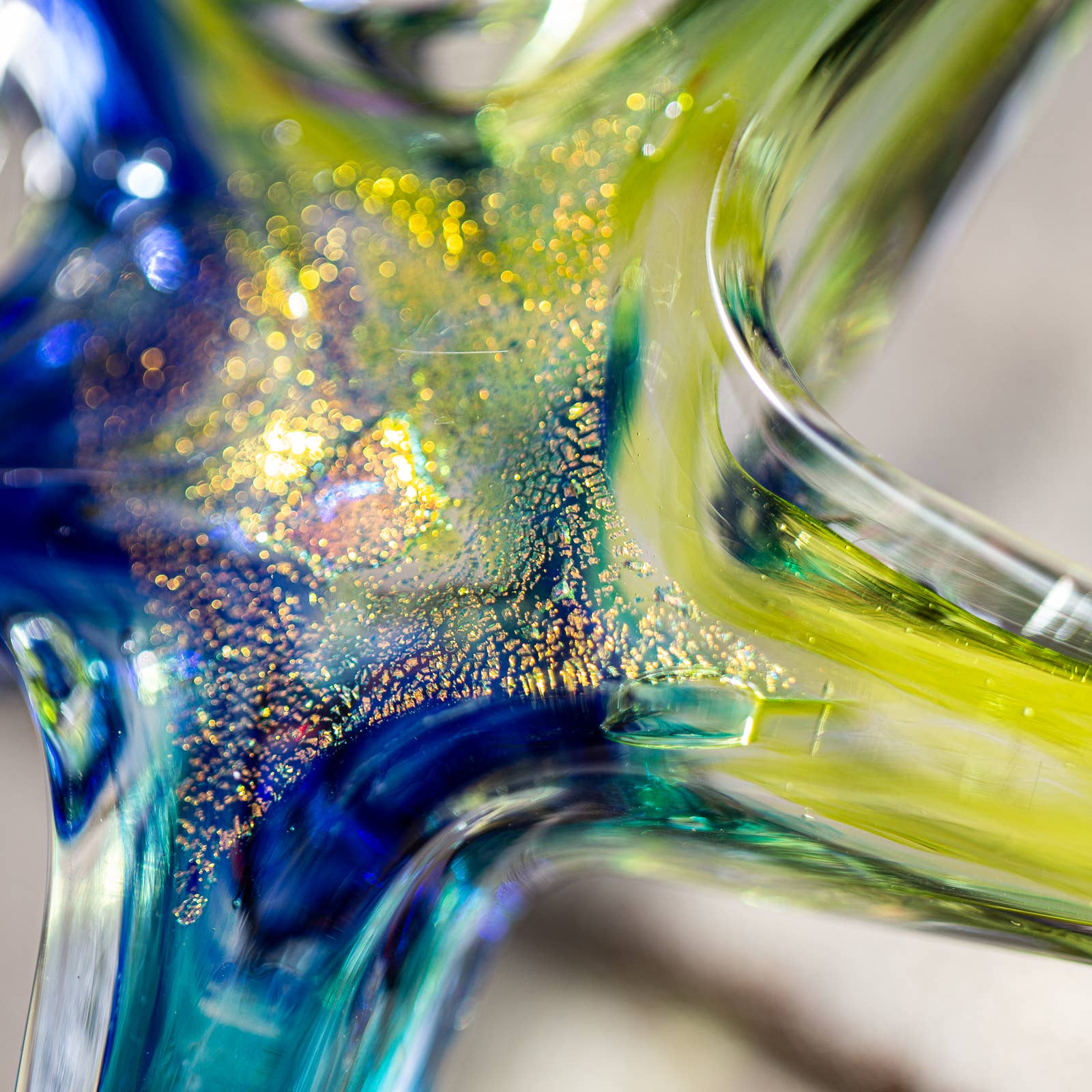 Mellow Monkey hand-blown glass star ornament featuring swirling blue and yellow glass with shimmering gold flecks.