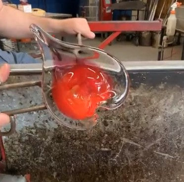 Mellow Monkey 5-inch hand-blown red glass heart ornament being crafted by an artisan in a glassblowing studio
