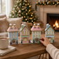 Mellow Monkey set of four handcrafted pastel light-up holiday houses with snowy roofs on a wooden table