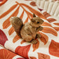 Mellow Monkey hand-painted resin squirrel figurine with textured brown fur sitting on a patterned autumn leaf fabric