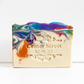 Mellow Monkey Deck The Halls handmade bar soap with a multicolored holiday lights swirl design on a white background.