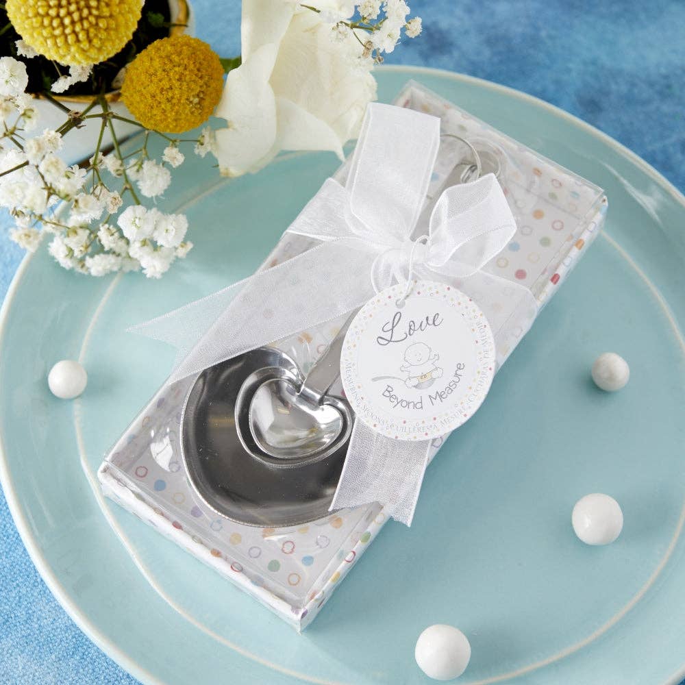 Mellow Monkey heart-shaped stainless steel measuring spoons in a gift box with a white ribbon for a baby shower favor.