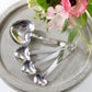 Mellow Monkey set of 4 stainless steel heart-shaped measuring spoons with engraved sentimental phrases on handles.