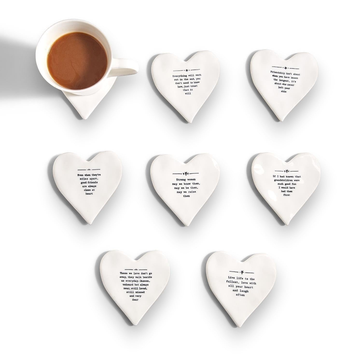 Mellow Monkey white porcelain heart-shaped coasters with black inspirational quotes and a coffee cup on one.