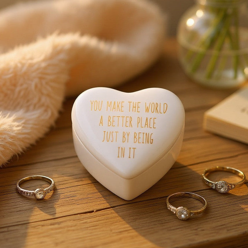 Mellow Monkey white ceramic heart-shaped trinket box with gold-foiled inscription on a wooden surface with rings.