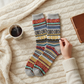 Mellow Monkey heather gray crew socks featuring a colorful Nordic-inspired fair isle pattern on a cozy knit blanket.