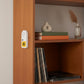 Mellow Monkey hidden cat meow prank device attached to a wooden bookshelf with adhesive backing.