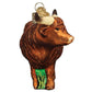 Mellow Monkey Highland Cow blown glass ornament with glitter accents and green grass detail. 4.25-in.