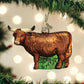Mellow Monkey Highland Cow blown glass holiday ornament with glittery brown coat and long horns, on a Christmas tree.